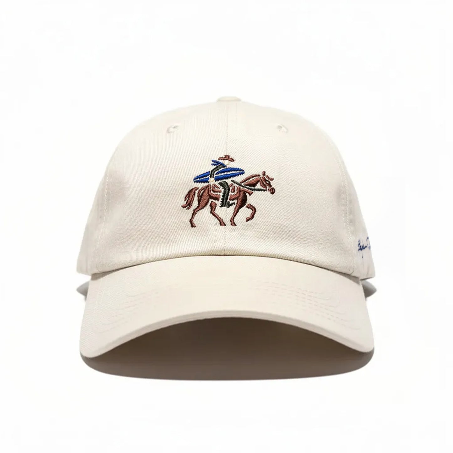 Beige cap with embroidered design of a surfing cowboy on a horse on a white background